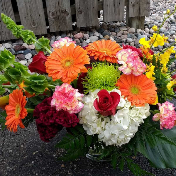 Mixed bouquet with orange gerbera daisies, red roses, white hydrangea, and yellow orchids