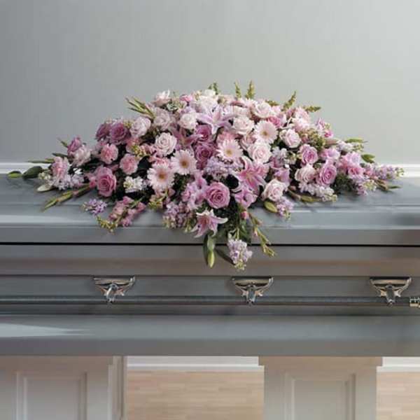 Pink and white floral casket spray on a gray coffin