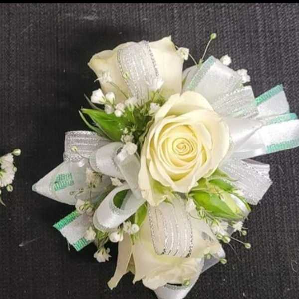 Two white rose boutonnieres with ribbon and baby's breath