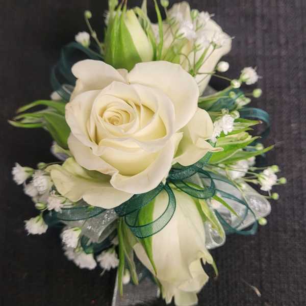 White rose corsage with green ribbon and small white filler flowers