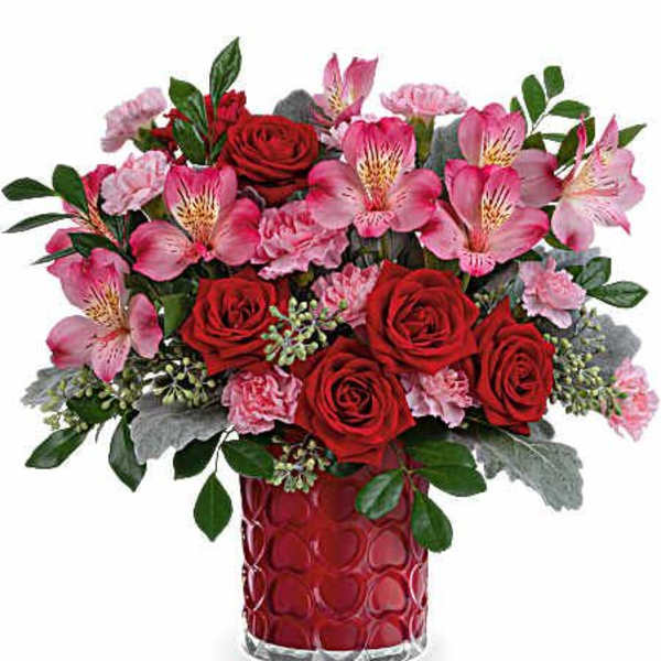 Bouquet of red roses and pink alstroemeria in a red glass vase