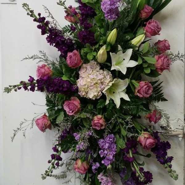 Tall floral spray with pink roses, white lilies, and purple blooms