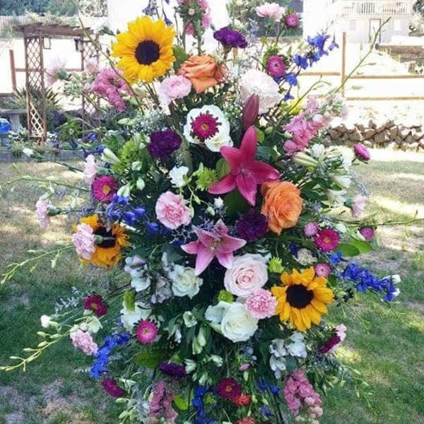 Tall standing floral spray with sunflowers, lilies, and mixed blooms