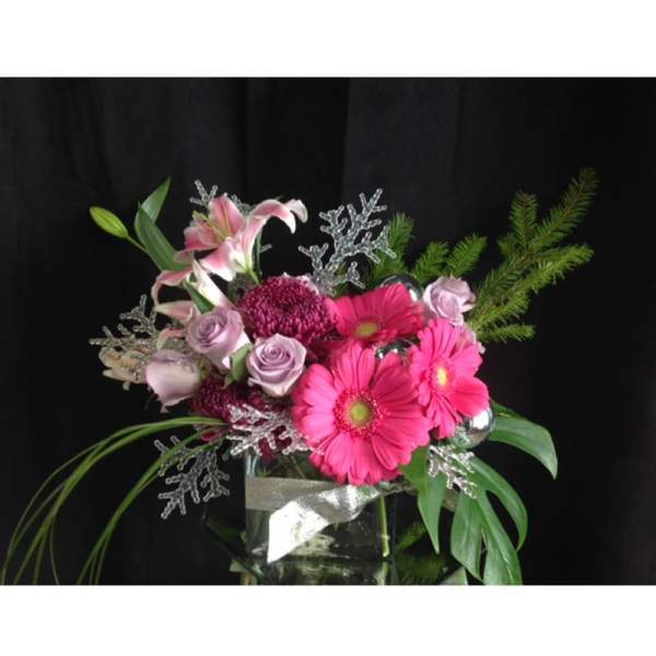 Pink gerbera daisies and roses in a glass vase with silver accents