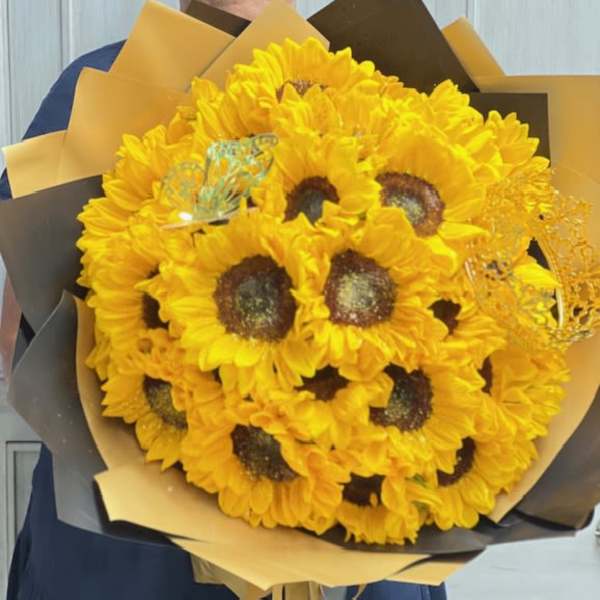 Bouquet of bright yellow sunflowers wrapped in black and gold paper