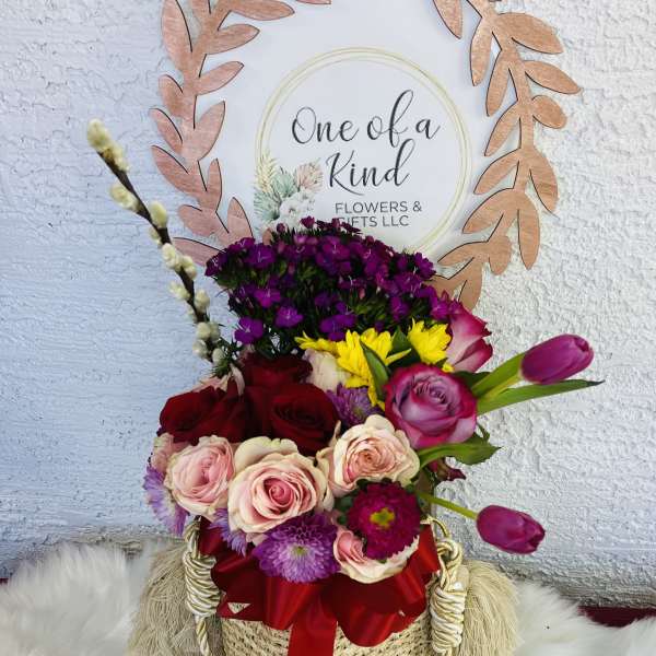Mixed bouquet in a woven basket with a red ribbon