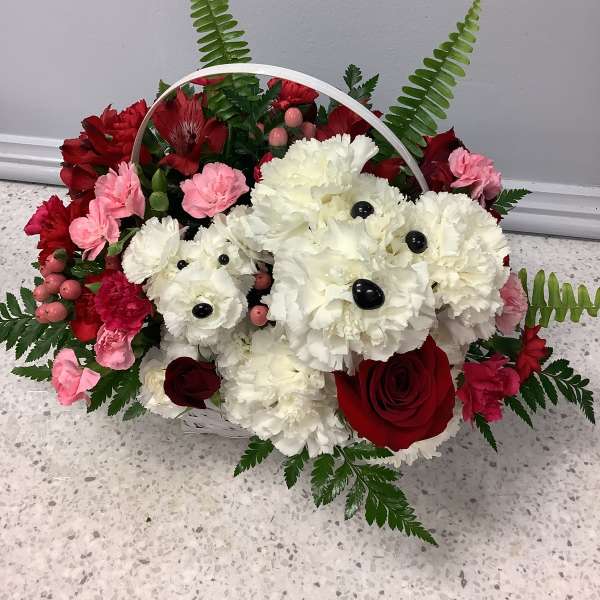 Basket arrangement of red, pink, and white flowers with fern accents