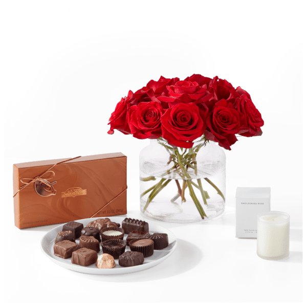 Red roses in a glass vase with chocolates and a candle