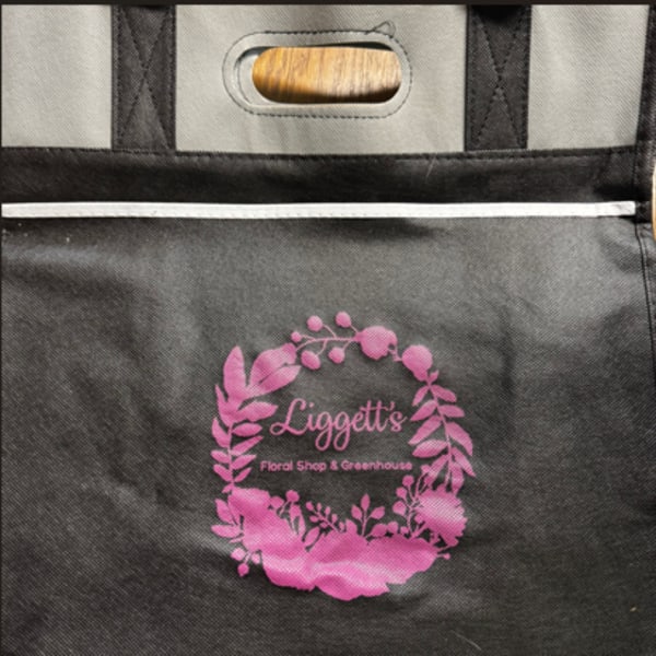 Black insulated tote bag with a pink floral shop logo