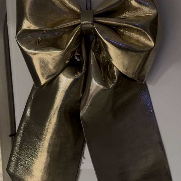 Large metallic gold bow on a white surface