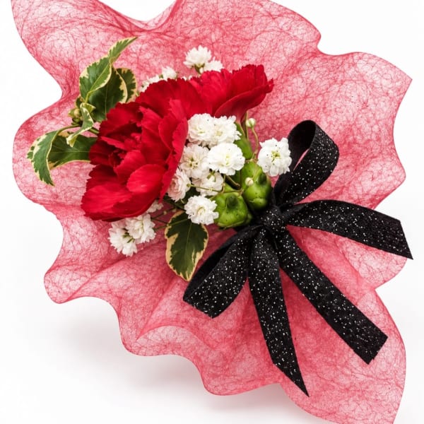 Red carnations with white filler flowers wrapped in pink mesh and a black ribbon