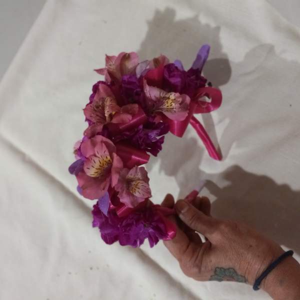 Pink and purple floral crown held in a hand