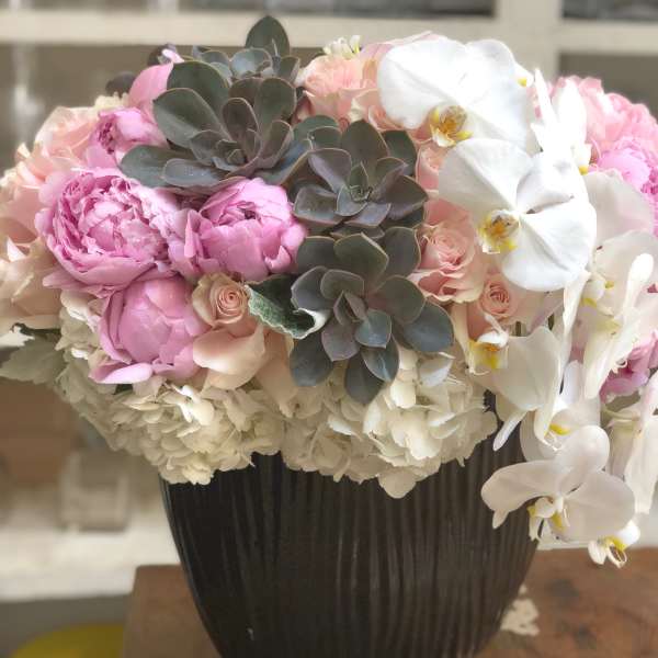 Pink peonies and white orchids in a dark vase