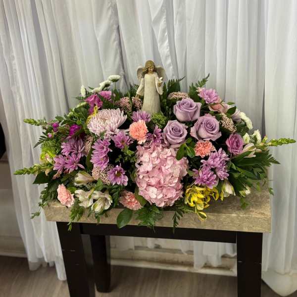 Sympathy floral arrangement with an angel figurine and pastel flowers