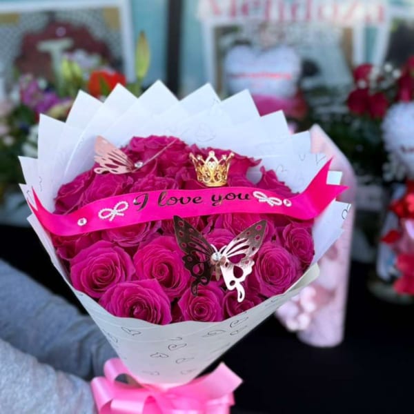 Hot pink rose bouquet wrapped in white paper with a pink ribbon