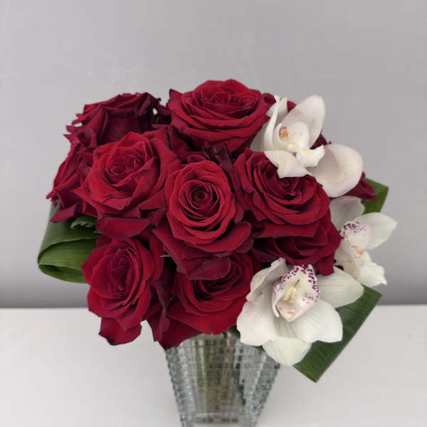 Red roses and white orchids in a clear glass vase