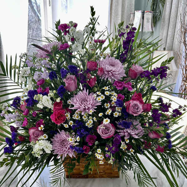 Large mixed bouquet in a woven basket with pink, purple, and white flowers