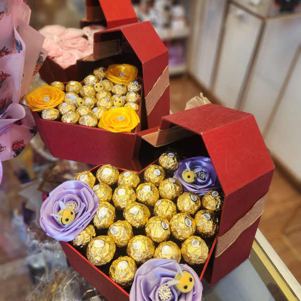 Heart-shaped gift boxes filled with chocolates and ribbon flowers