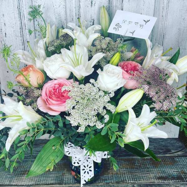 Bouquet of white lilies and pink roses in a vase with a ribbon