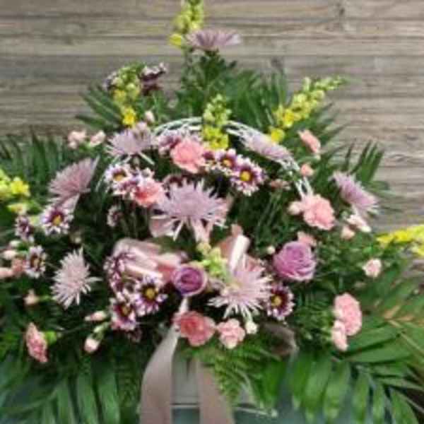 Pink and lavender funeral spray with mixed flowers and greenery
