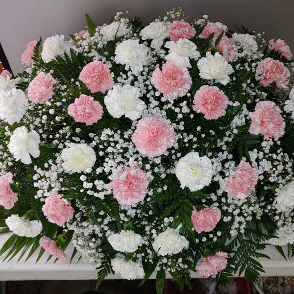 Pink and white carnation casket spray with baby's breath