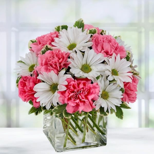 Pink carnations and white daisies in a square glass vase
