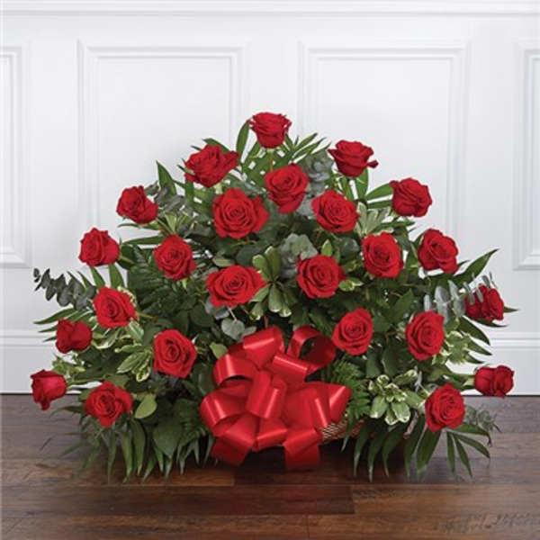 Red roses arranged in a low basket with a large red bow