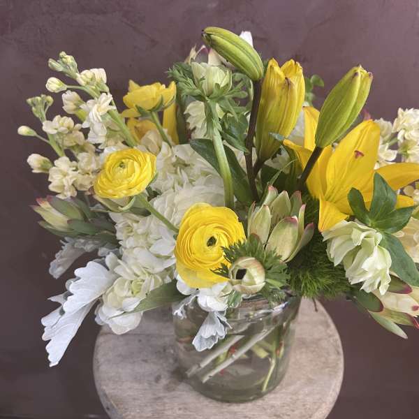 Yellow lilies and white flowers in a clear glass vase