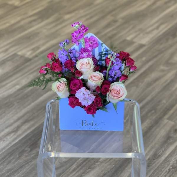 Mixed pink and purple roses arranged in a blue box