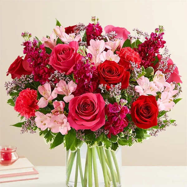 Bouquet of pink and red roses with pale pink flowers in a clear glass vase