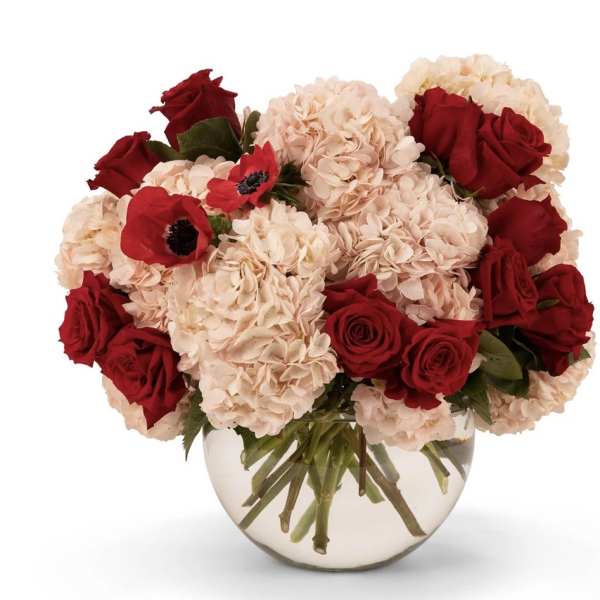Bouquet of red roses and pale pink hydrangeas in a clear glass vase