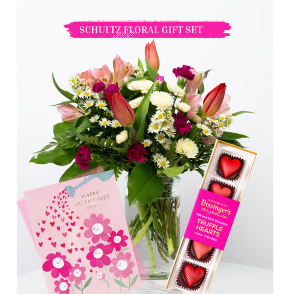 Mixed bouquet in a glass vase with a Valentine card and heart-shaped chocolates