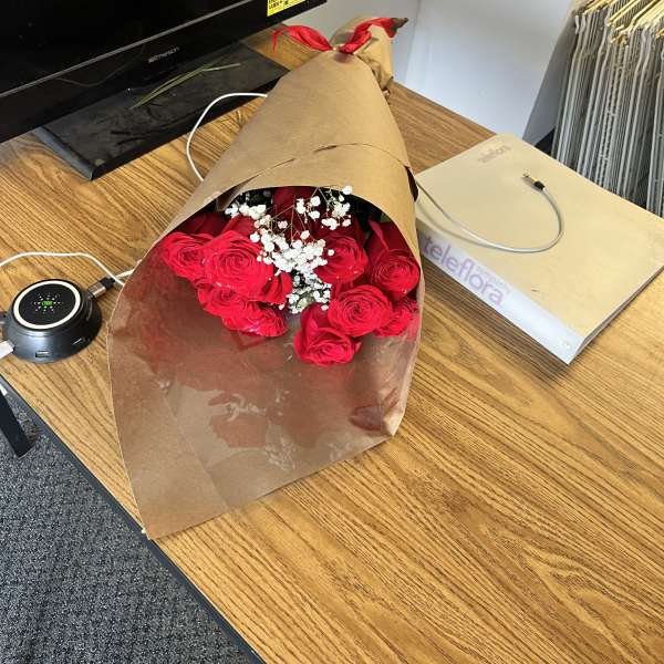 Bouquet of red roses with white baby's breath in brown paper wrap