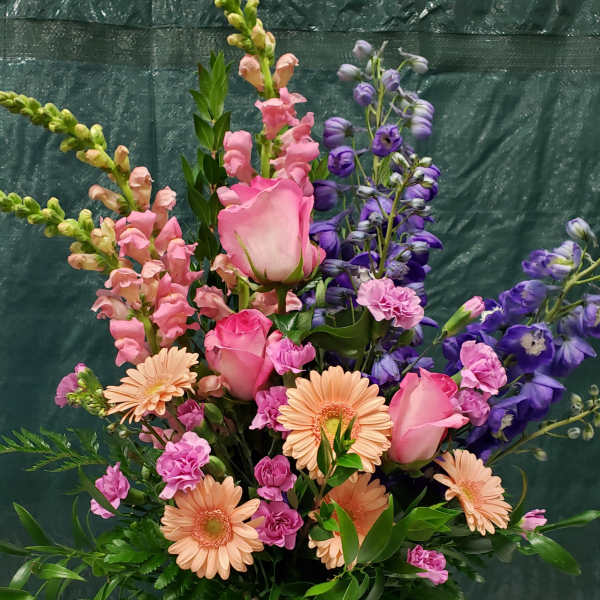 Tall mixed bouquet in a glass vase with pink roses and peach daisies