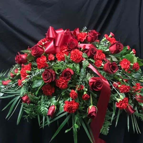 Large red rose and carnation arrangement with ribbon on a black backdrop