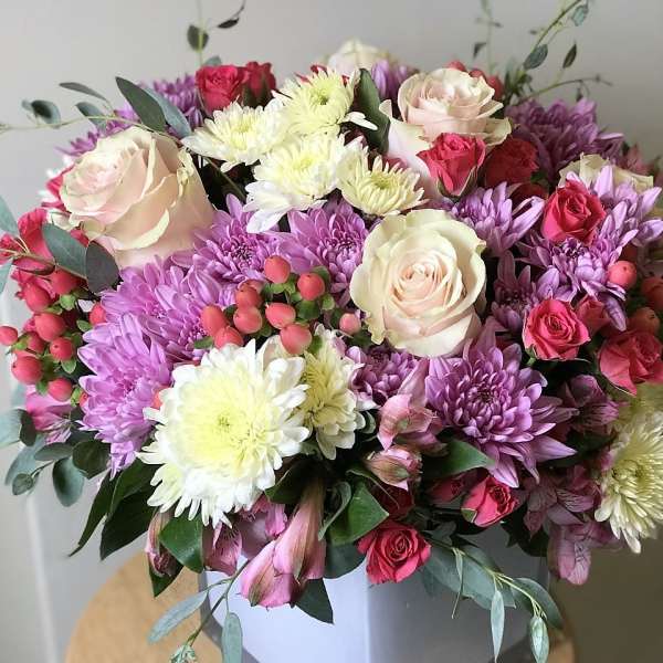 Bouquet of pink roses and purple chrysanthemums in a white box