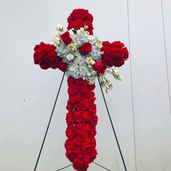 Red floral cross on a stand with white and blue flowers