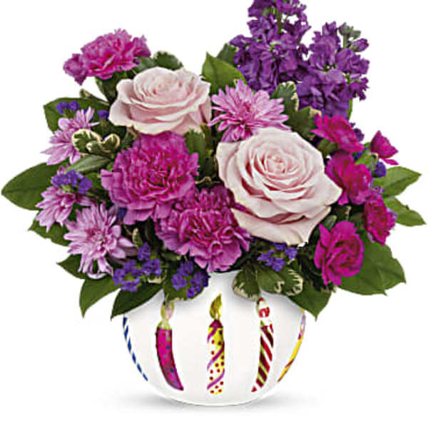 Pink and purple flower arrangement in a white vase with candle designs