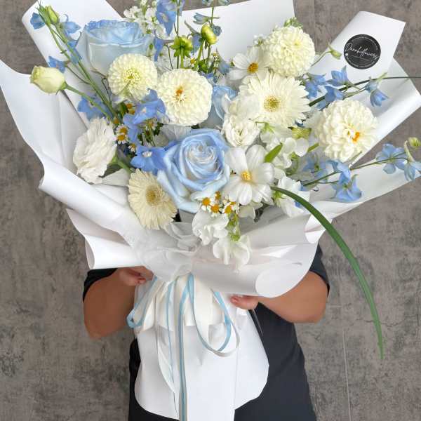 Blue and white bouquet with roses, daisies, and pom flowers in white wrap