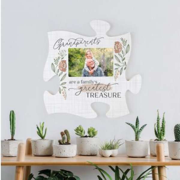 Decorative puzzle-piece sign with a family photo and potted succulents below