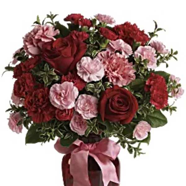 Red roses and pink carnations in a vase with a pink ribbon