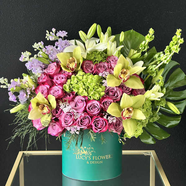 Pink roses and yellow orchids in a teal hatbox