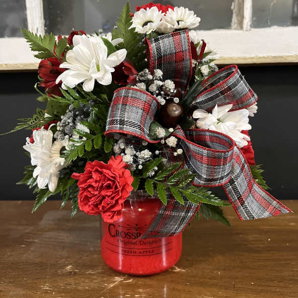 Red and white flower arrangement in a red jar with plaid ribbon