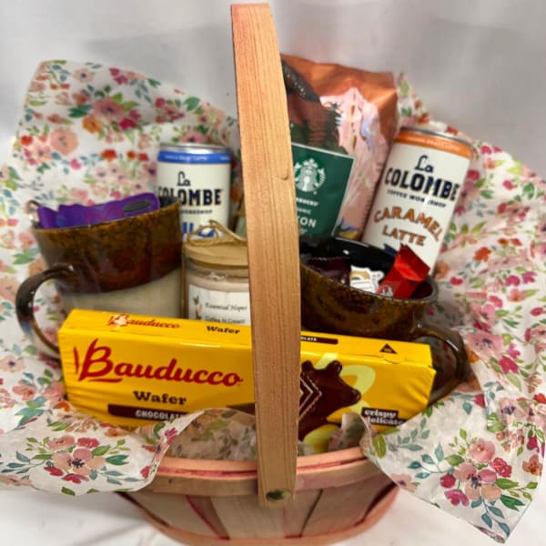Gift basket with coffee cans, cookies, and a candle in floral wrap