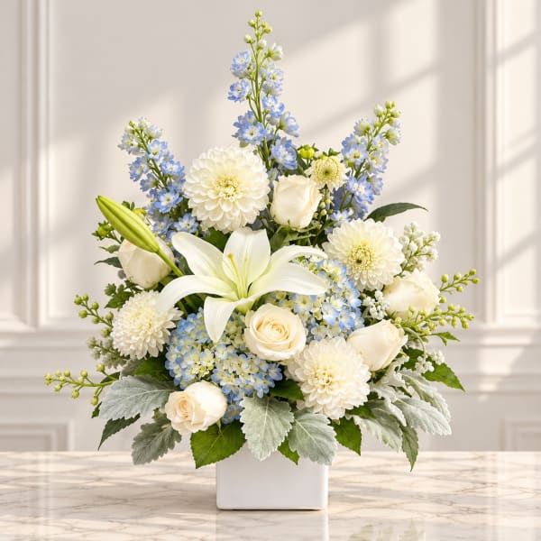 White and blue floral arrangement in a square white vase