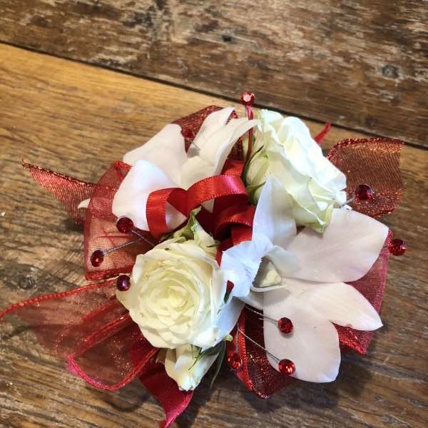 White roses with white orchids and red ribbon accents