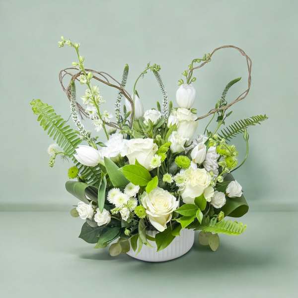 White floral arrangement in a white vase with looping twig accents