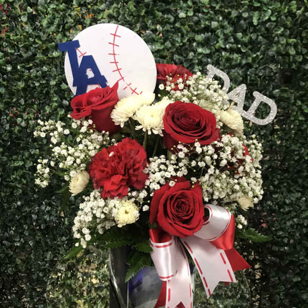 Red roses and white flowers in a vase with baseball-themed decorations