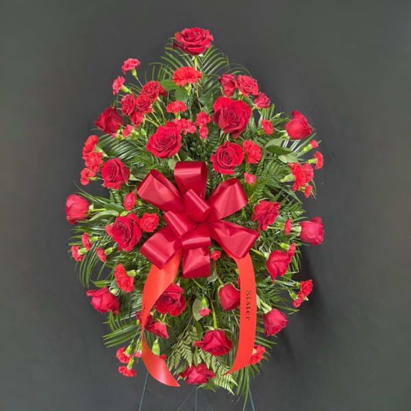 Red rose and carnation standing spray with a ribbon bow