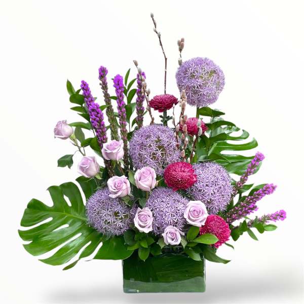 Purple and pink floral arrangement in a glass vase